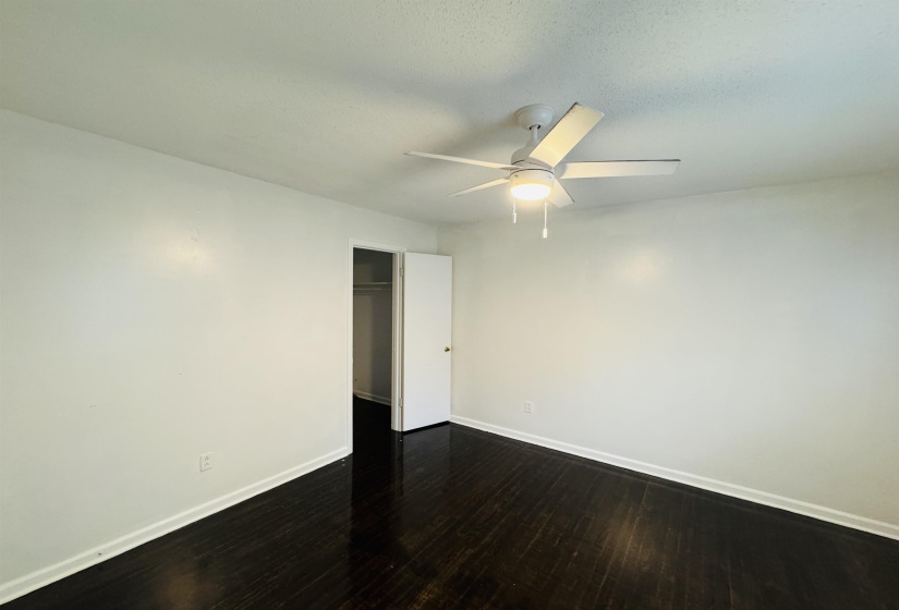 Unfurnished room with dark wood-style flooring, baseboards, and a ceiling fan