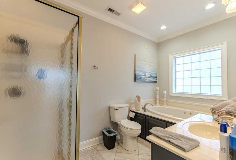 Bathroom featuring vanity, a shower stall, ornamental molding, light tile patterned flooring, and a whirlpool tub