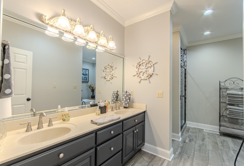 Bathroom featuring ornamental molding, double vanity, a shower with shower door, wood tiled floors, and recessed lighting