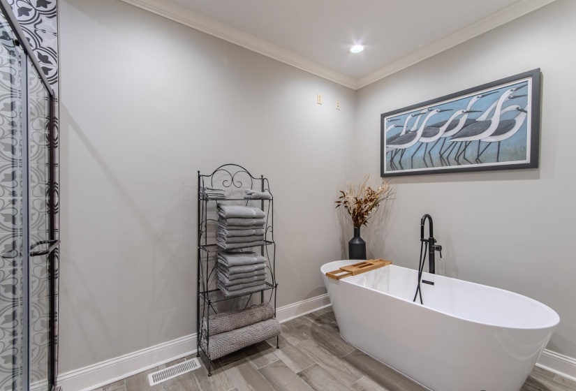 Bathroom with crown molding, wood finished floors, a freestanding tub, and recessed lighting