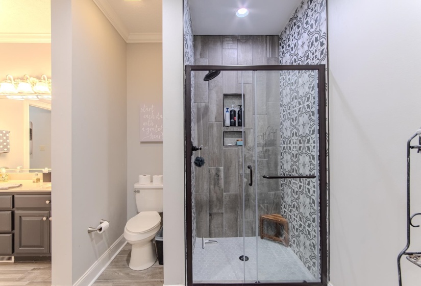 Bathroom featuring vanity, light wood-style floors, a stall shower, and ornamental molding
