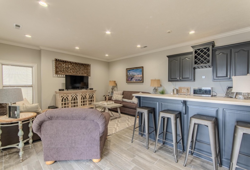 Living area with ornamental molding, recessed lighting, and wood finish floors