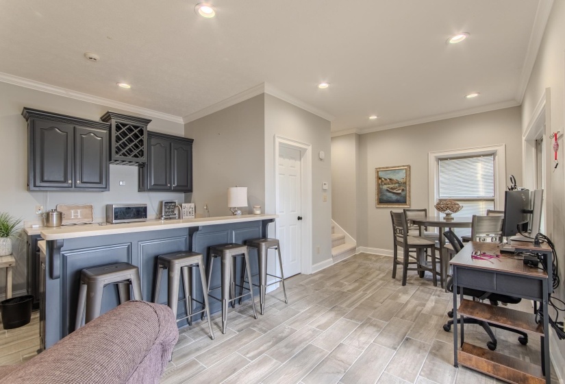 Kitchen with light countertops, a breakfast bar, ornamental molding, recessed lighting, and wood tiled floors