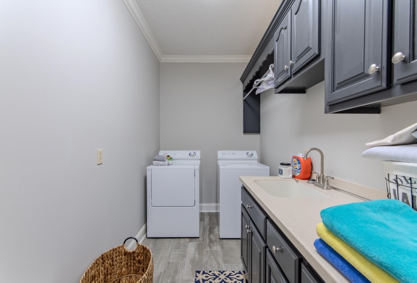 Laundry room with ornamental molding, cabinet space, and washer and clothes dryer