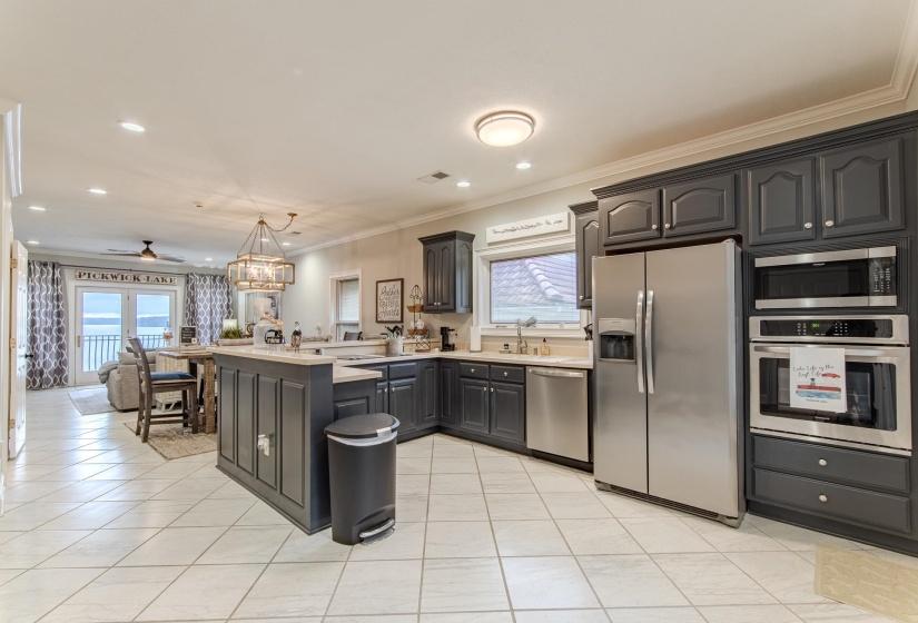 Kitchen featuring a peninsula, stainless steel appliances, crown molding, open floor plan, and light tile patterned flooring