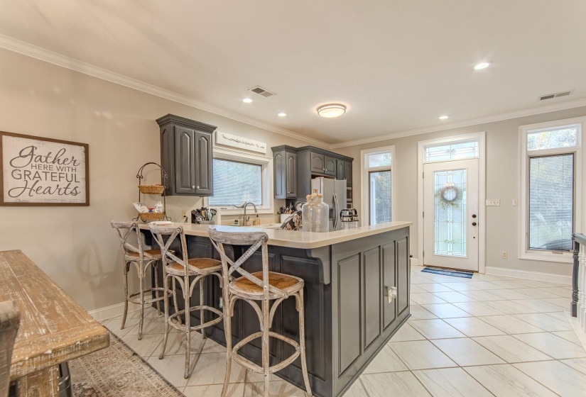 Kitchen featuring a kitchen breakfast bar, crown molding, a peninsula, light tile patterned floors, and stainless steel fridge