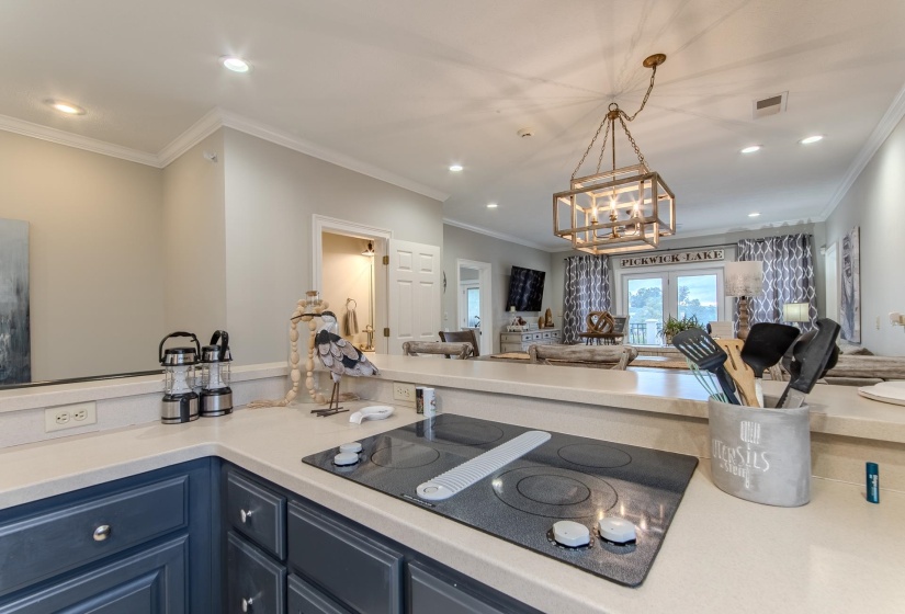 Kitchen with open floor plan, black electric stovetop, recessed lighting, ornamental molding, and pendant lighting
