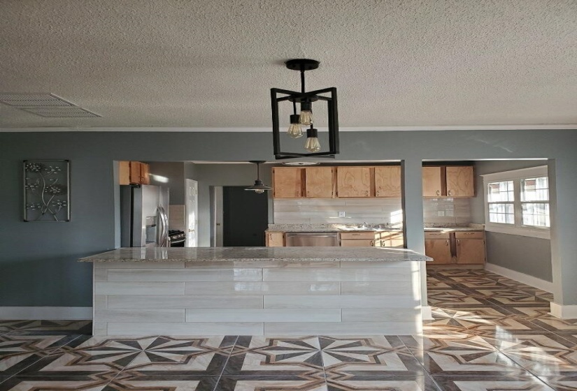 Kitchen with pendant lighting, a textured ceiling, decorative backsplash, stainless steel appliances, and dark parquet floors