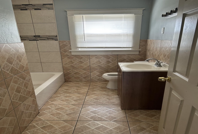 Bathroom with tile patterned flooring, toilet, vanity, tile walls, and wainscoting