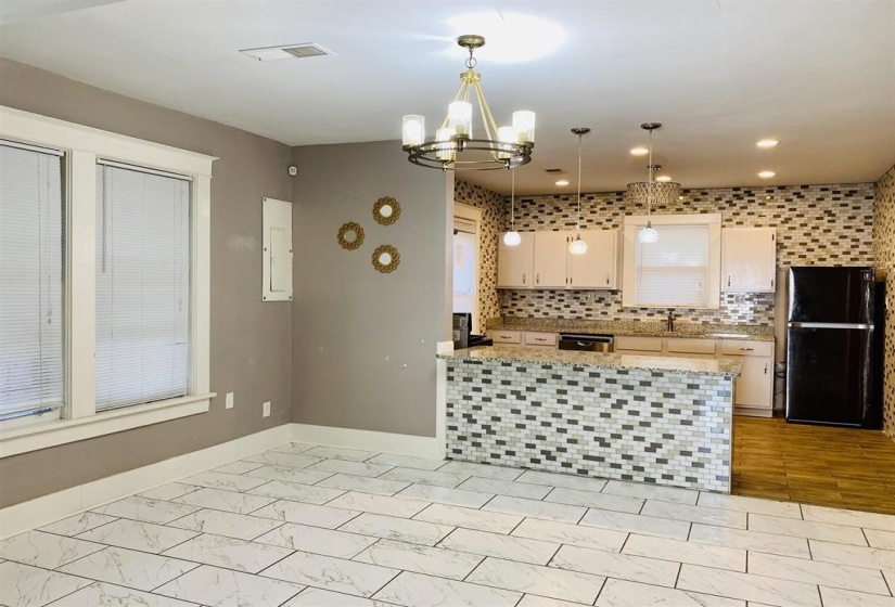 Kitchen featuring freestanding refrigerator, decorative backsplash, decorative light fixtures, a chandelier, and dishwasher