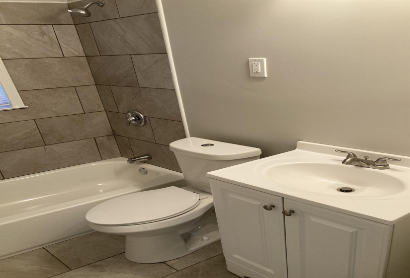 Bathroom with light tile patterned floors,  shower combination, and vanity