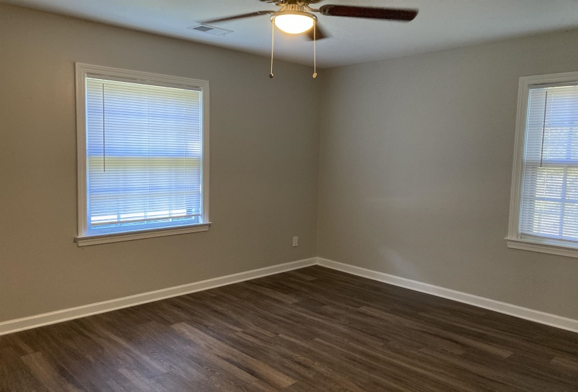 Empty room with dark wood finished floors and a ceiling fan