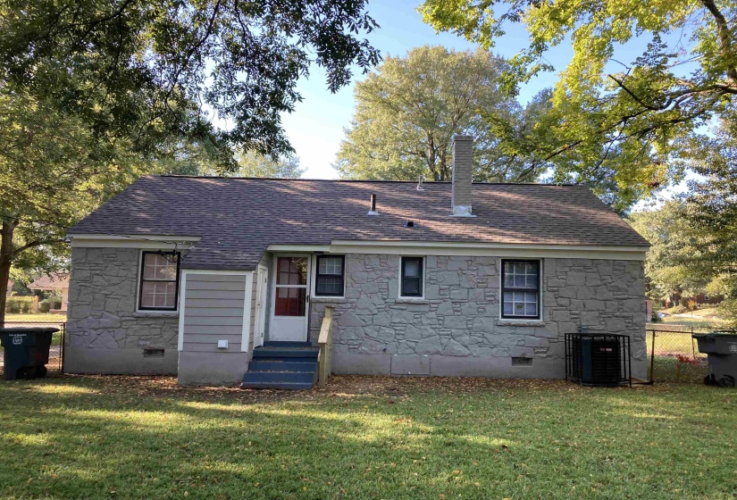 Rear view of property with crawl space, stone siding, and a lawn