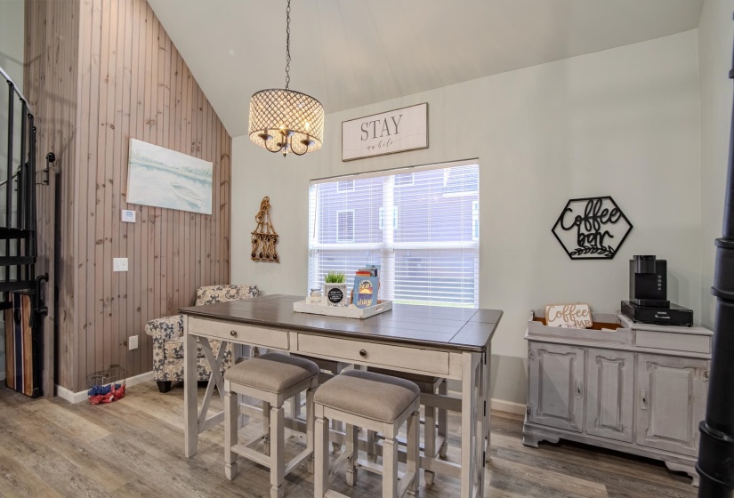 Dining space featuring wood walls, wood finished floors, a chandelier, and high vaulted ceiling