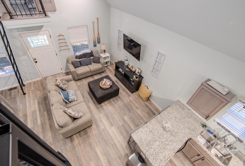 Living area with plenty of natural light, a towering ceiling, and light wood-style floors