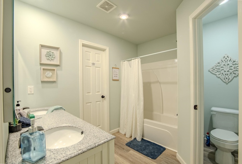 Bathroom featuring double vanity, light wood-type flooring, and shower / bath combo