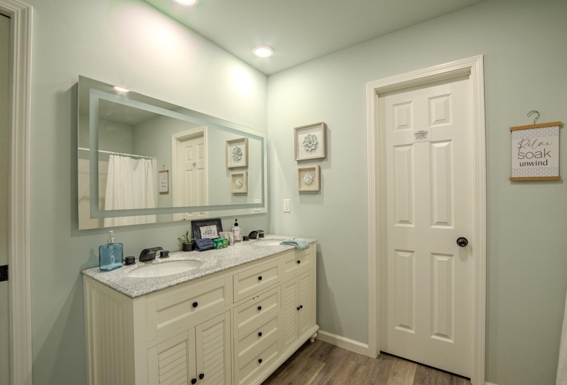 Bathroom featuring dark wood-style flooring, double vanity, and a shower with shower curtain