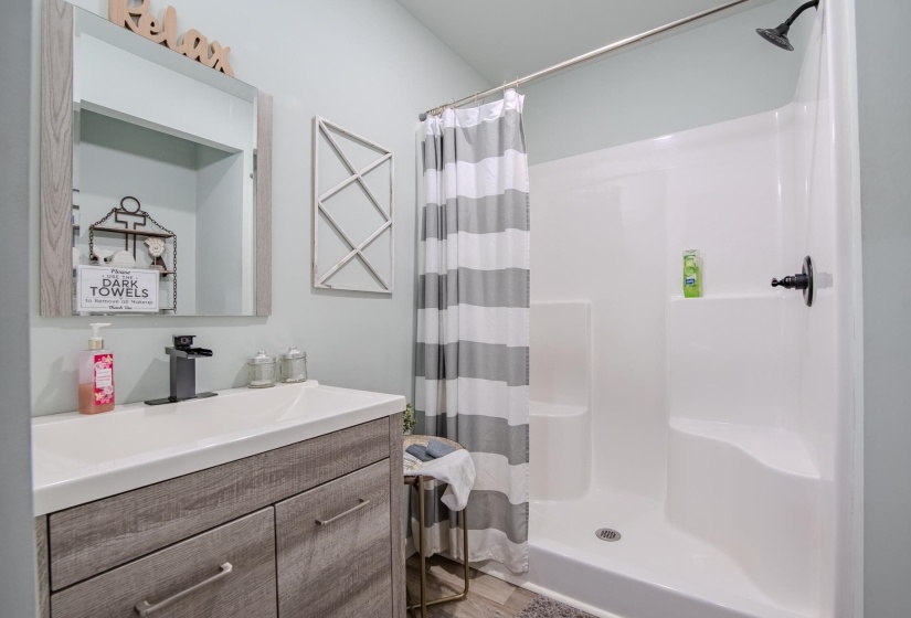 Bathroom with vanity, a stall shower, and light wood-style flooring