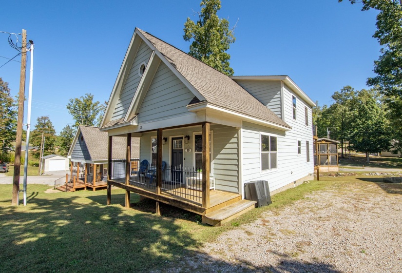 Rear view of house with roof with shingles, a lawn, an outdoor structure, and covered porch