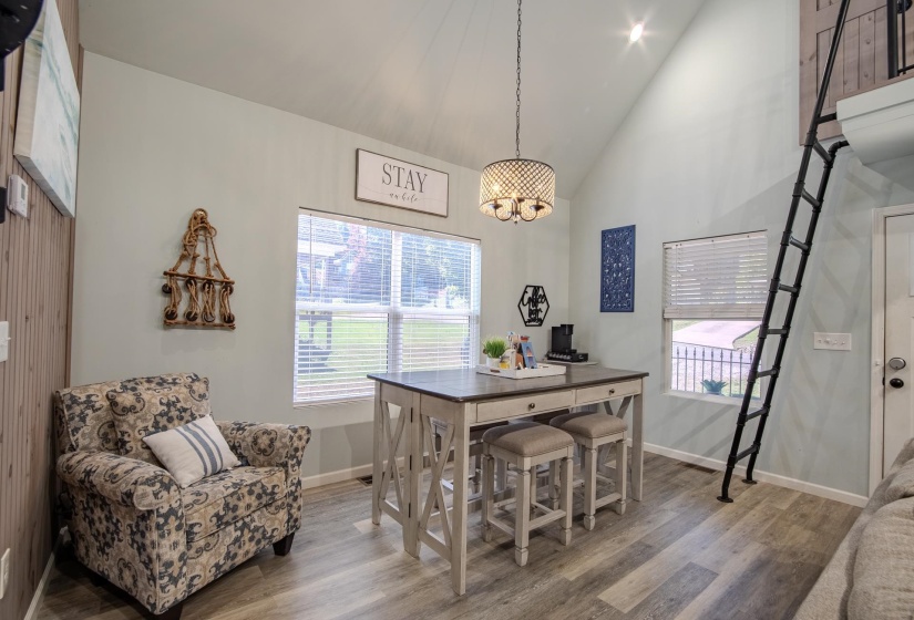 Dining area featuring high vaulted ceiling, plenty of natural light, wood finished floors, and a chandelier