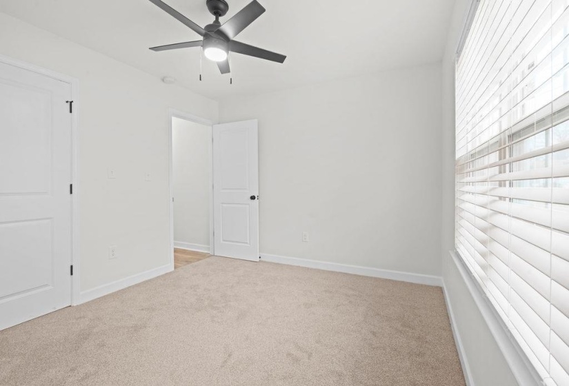 Unfurnished bedroom with light colored carpet and a ceiling fan