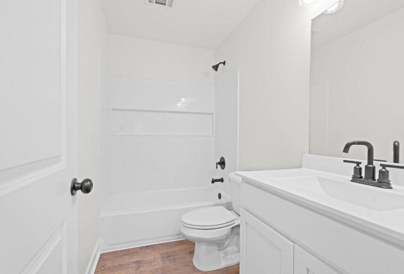 Full bath featuring tub / shower combination, vanity, and dark wood-type flooring