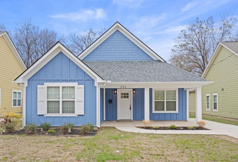 Bungalow with board and batten siding, roof with shingles, a front yard, and covered porch