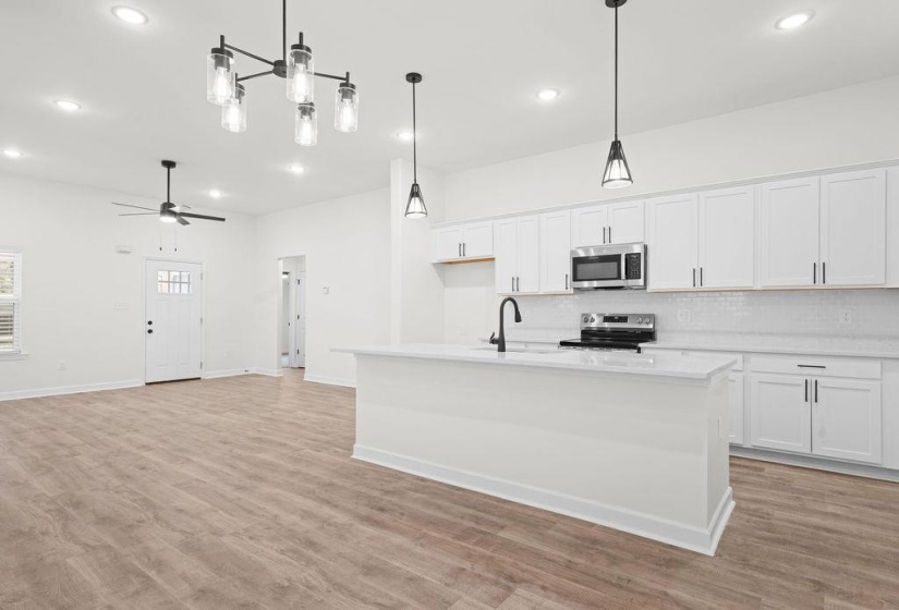 Kitchen with white cabinets, stainless steel appliances, an island with sink, light wood-type flooring, and recessed lighting