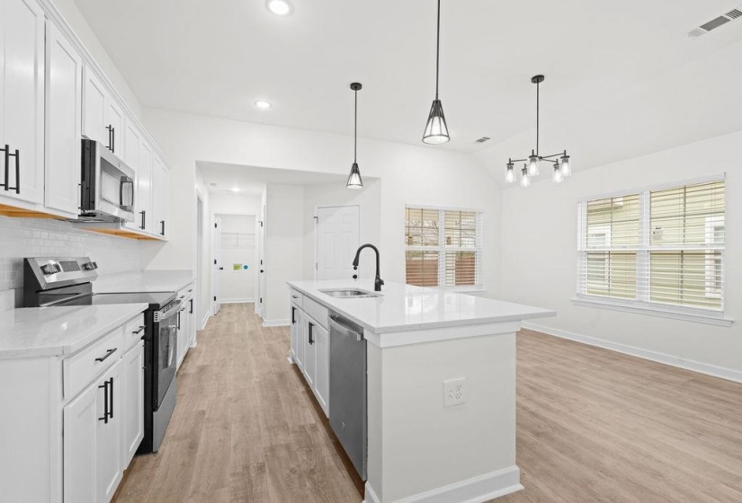 Kitchen featuring appliances with stainless steel finishes, white cabinets, pendant lighting, light wood finished floors, and lofted ceiling