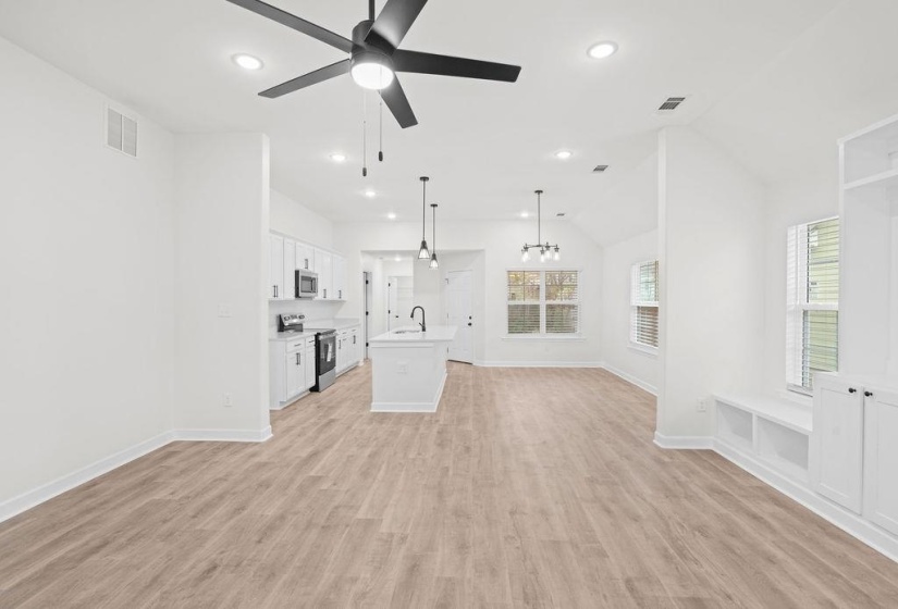 Unfurnished living room featuring light wood-type flooring, a chandelier, vaulted ceiling, recessed lighting, and a ceiling fan