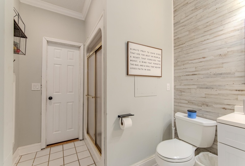 Full bathroom featuring a shower stall, light tile patterned flooring, vanity, ornamental molding, and wooden walls