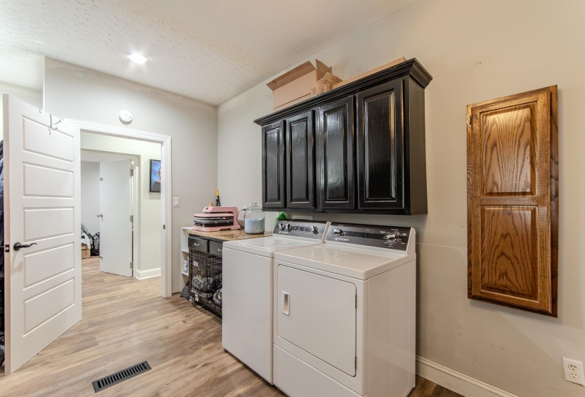 Laundry room with light wood-type flooring, washer and clothes dryer, cabinet space, a textured ceiling, and recessed lighting