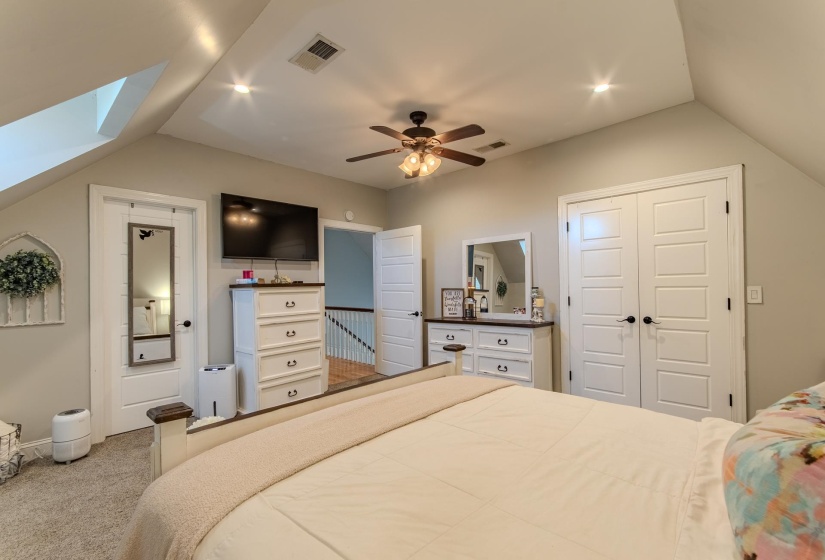 Carpeted bedroom with lofted ceiling, a closet, ceiling fan, and a skylight