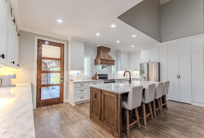 Kitchen featuring white cabinets, tasteful backsplash, light stone counters, a breakfast bar area, and a kitchen island with sink