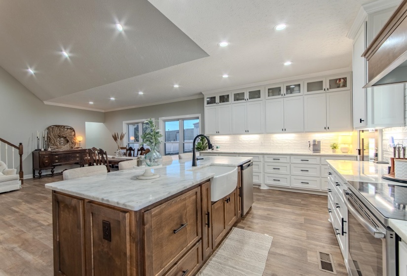 Kitchen featuring appliances with stainless steel finishes, glass insert cabinets, white cabinetry, open floor plan, and tasteful backsplash