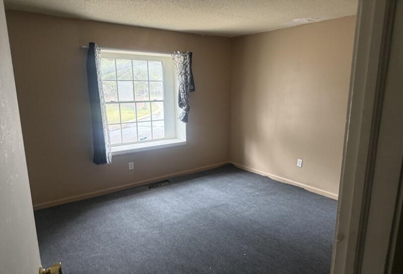 Empty room with a textured ceiling and carpet floors