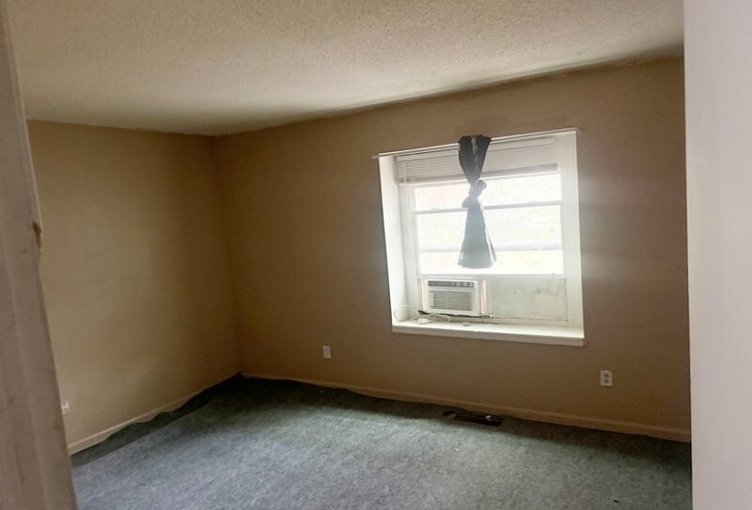 Empty room with a textured ceiling, carpet flooring, and cooling unit
