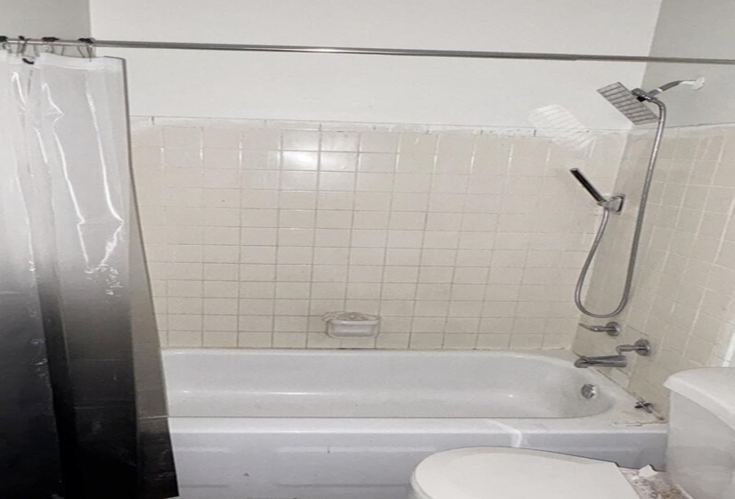 Bathroom featuring toilet and shower / bath combination with curtain