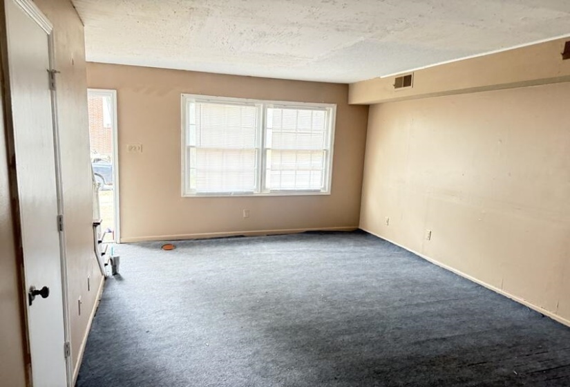 Carpeted empty room with a textured ceiling and baseboards