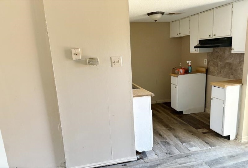 Kitchen featuring white cabinets, light wood-style flooring, light countertops, and under cabinet range hood
