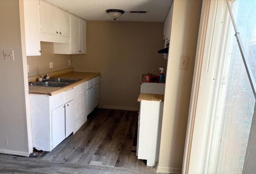 Kitchen featuring dark wood-style floors, white cabinetry, light countertops, and a textured ceiling
