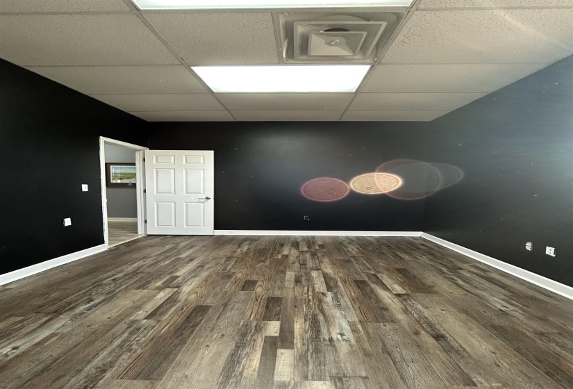 Unfurnished room with a drop ceiling and dark wood-type flooring