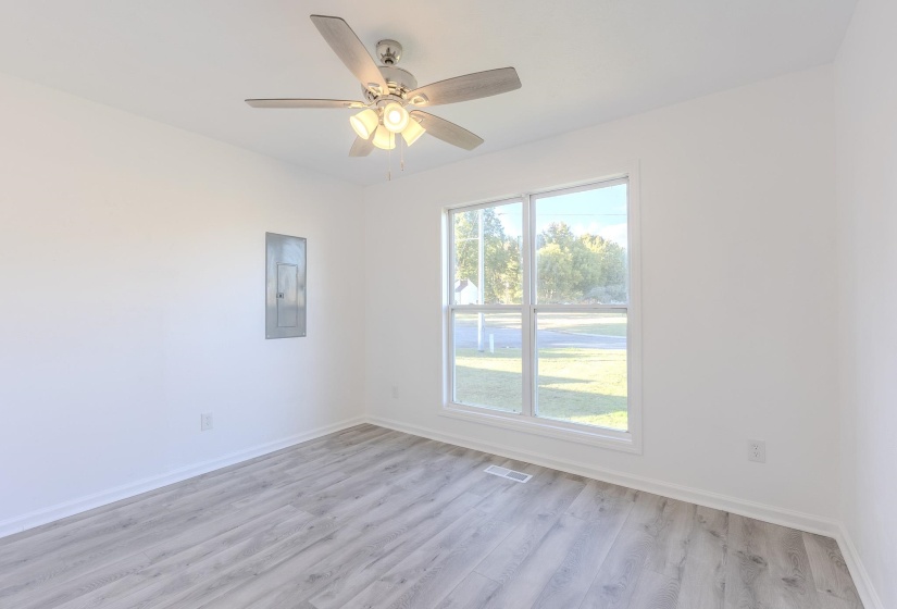 Unfurnished room with light wood-style floors, electric panel, and a ceiling fan