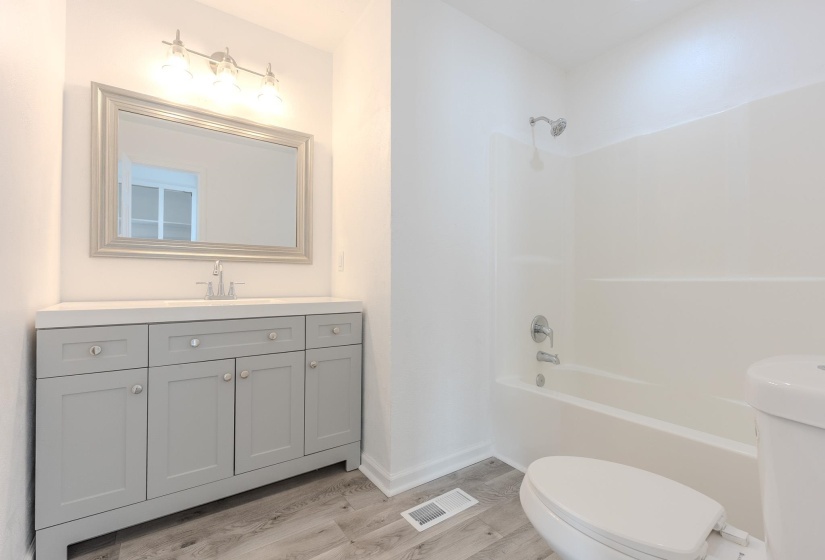 Full bath with vanity, light wood-style flooring, and shower / bathtub combination