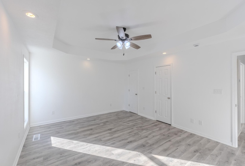 Empty room featuring a tray ceiling, recessed lighting, light wood-style flooring, and ceiling fan