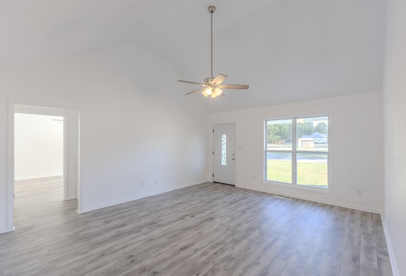 Unfurnished living room with light wood-type flooring, ceiling fan, and high vaulted ceiling