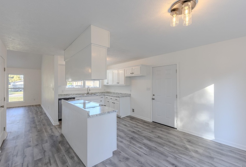 Kitchen with white cabinets, light countertops, light wood-style flooring, and a center island