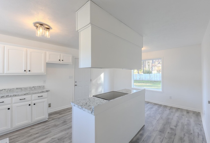 Kitchen featuring white cabinets, light wood finished floors, and black electric stovetop