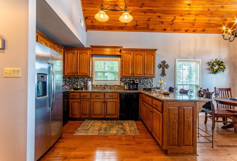 Kitchen with brown cabinets, a peninsula, a kitchen bar, tasteful backsplash, and wood ceiling