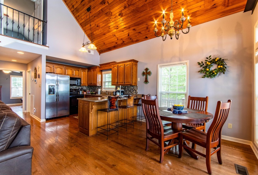 Dining space with wooden ceiling, high vaulted ceiling, wood-type flooring, and a chandelier